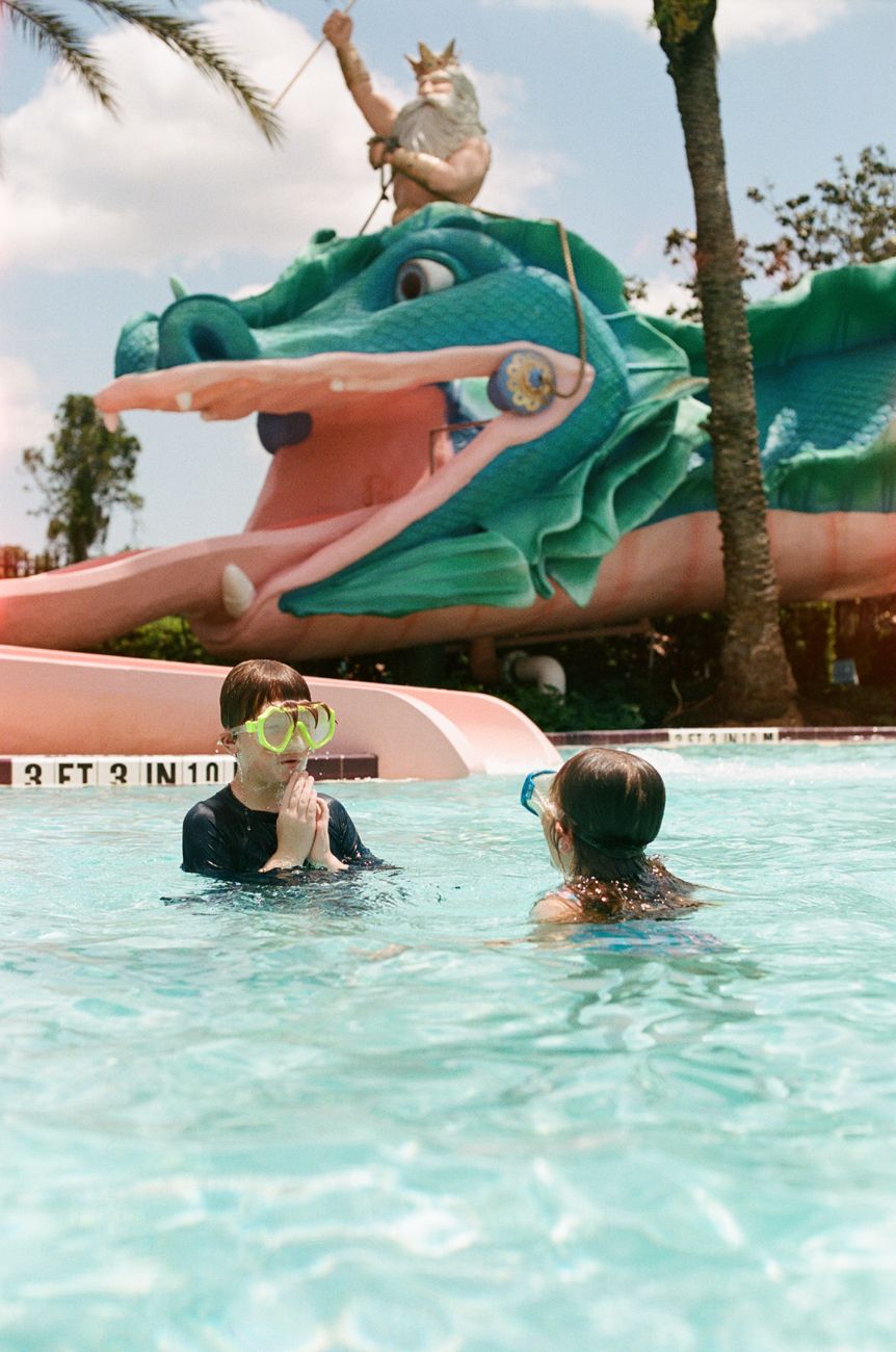 Swimming pool with large green alligator water feature at Disney resort.