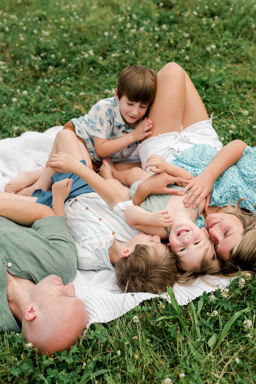 family laying together in open field for photography