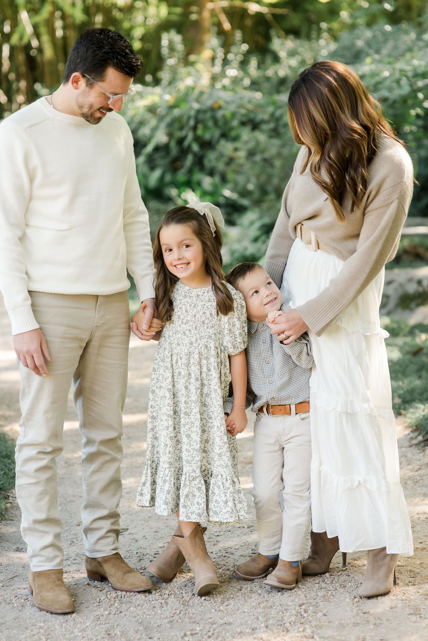 Family wearing coordinated white and beige outfits poses together for casual outdoor portraits.
