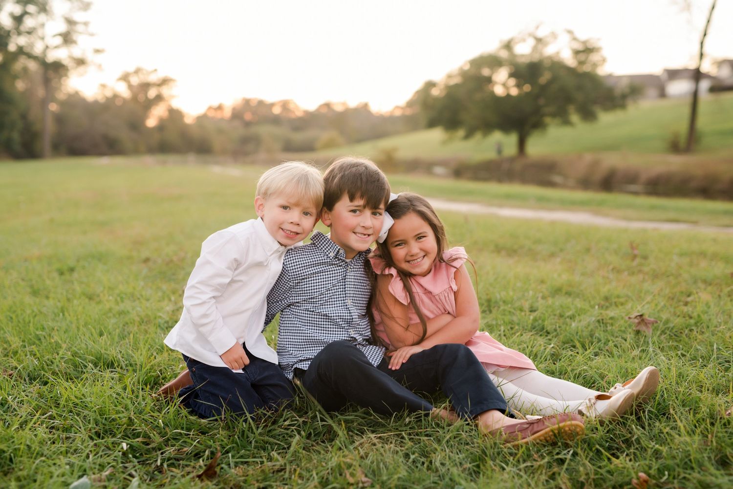 Family lying together on grass during sunset photo session.