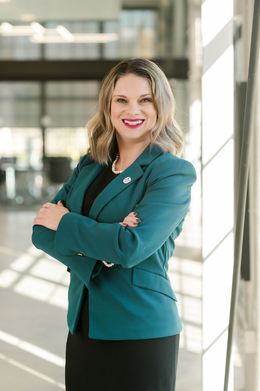 Professional headshots of a person in a teal blazer and black top against a bright modern interior.