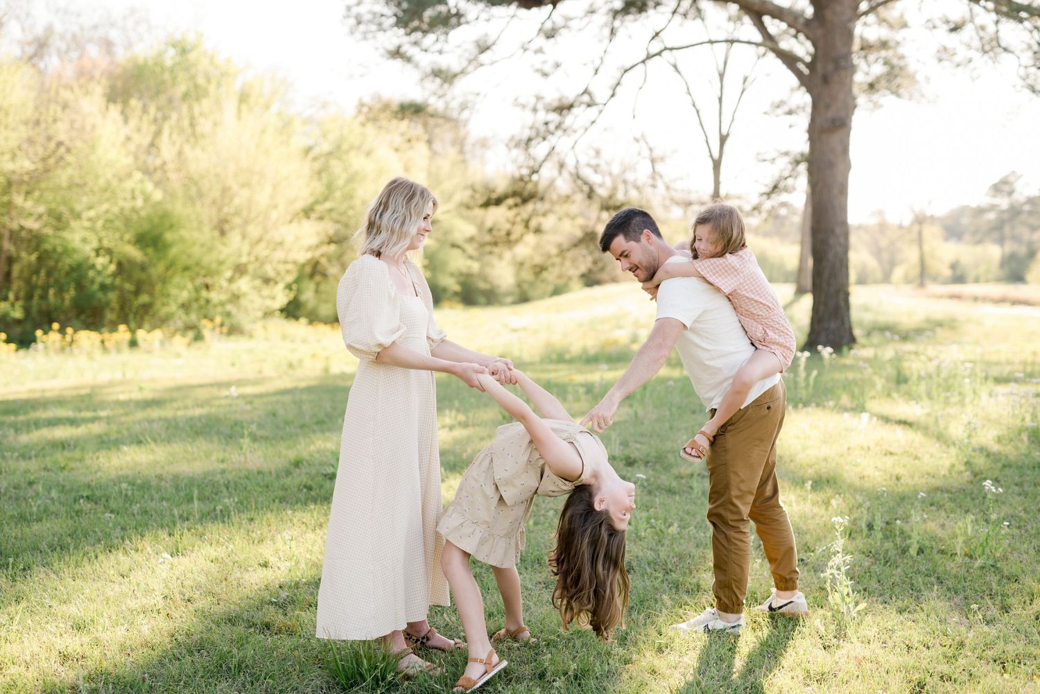 A family plays and laughs together while enjoying a tender moment in nature.