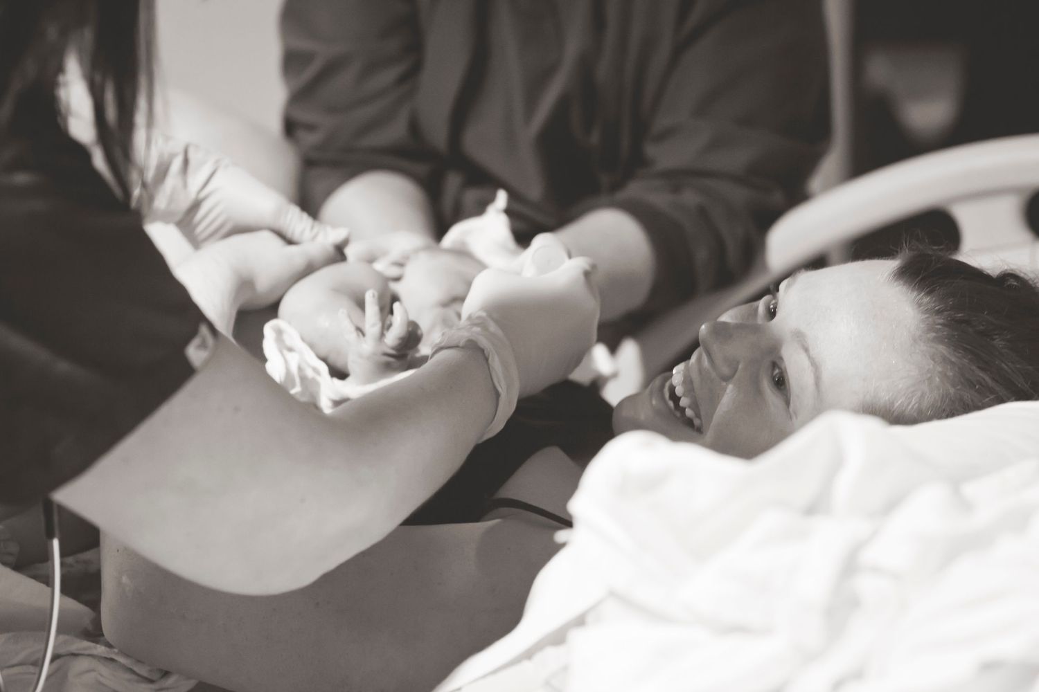 Healthcare providers examining newborn baby in black and white hospital scene.