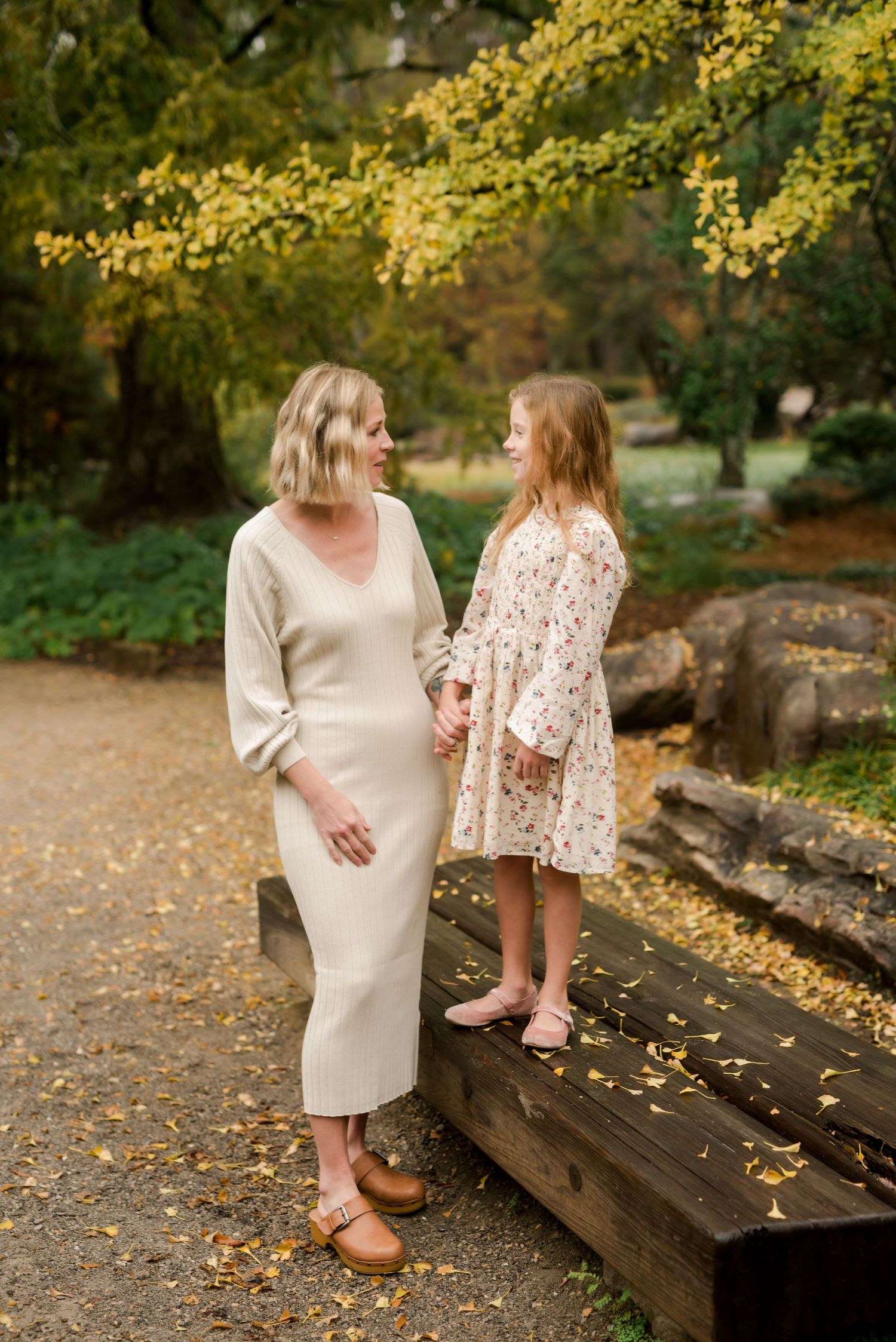 Two people share a moment together on wooden steps surrounded by autumn leaves.