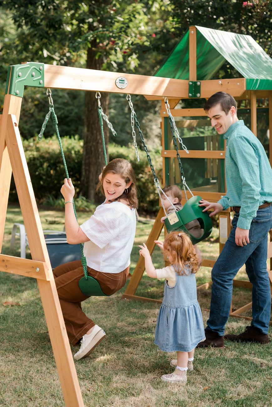 Wooden swing set in a backyard garden with children playing and enjoying outdoor activities.