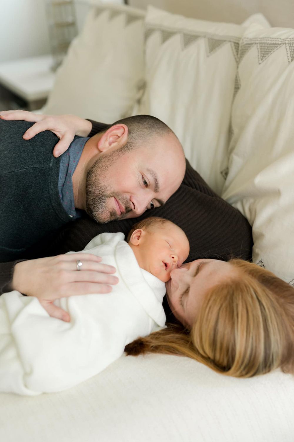 Family portrait in sunlit stairway with natural light streaming through windows.