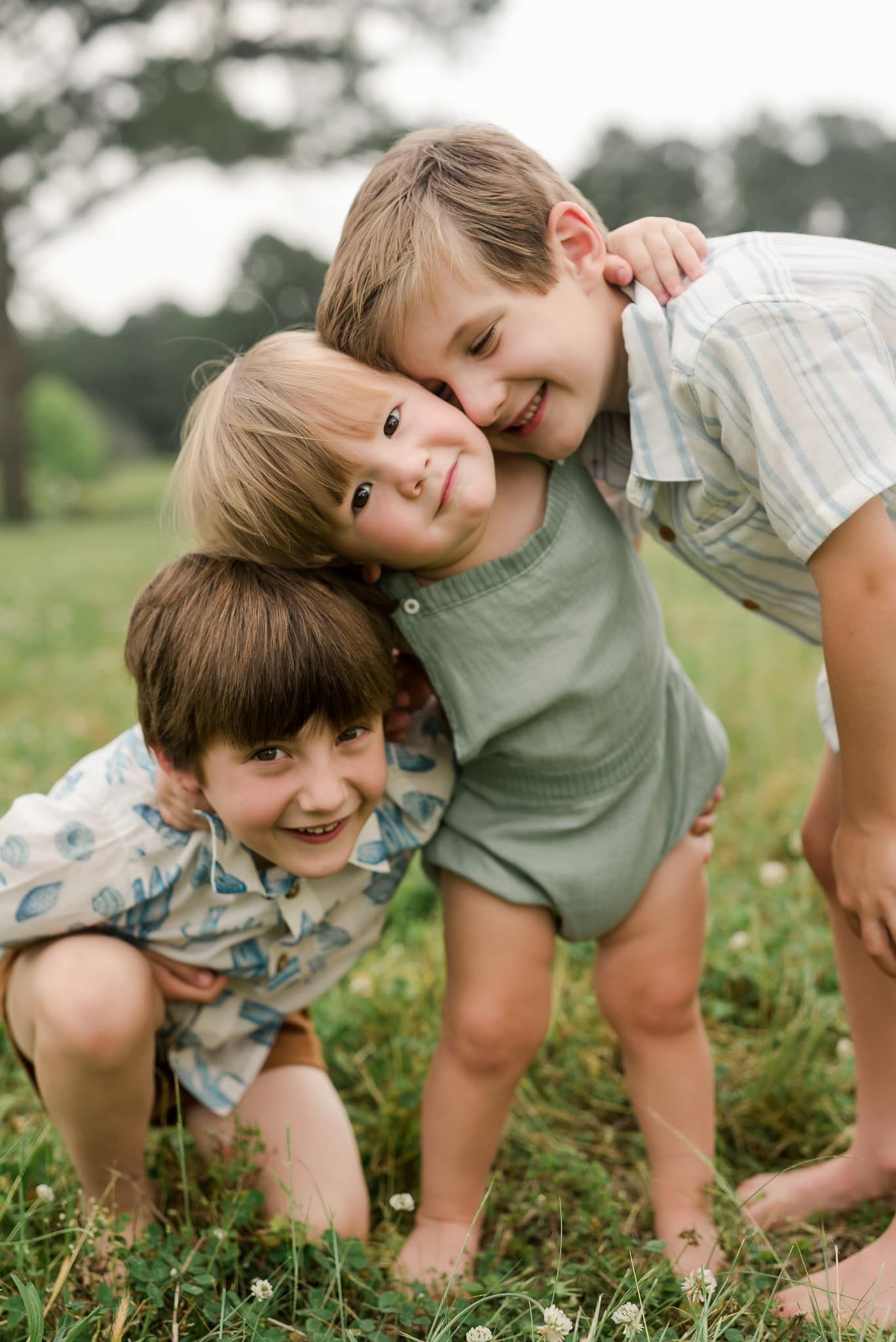 Children playing and laughing together while crouching in green summer field.