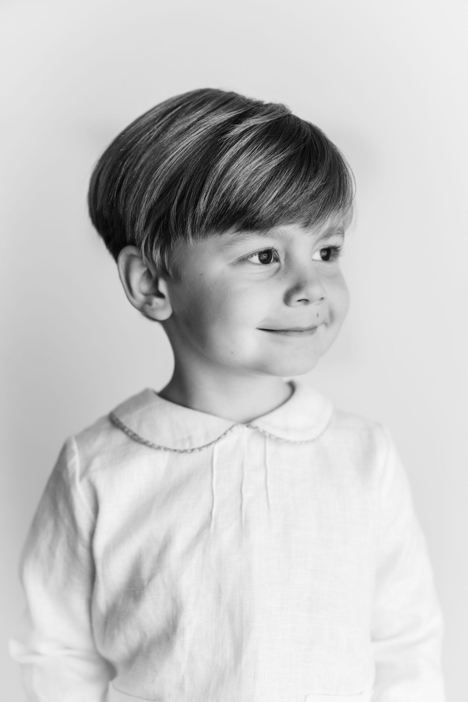 Black and white portrait of child in white collared shirt with short styled hair.