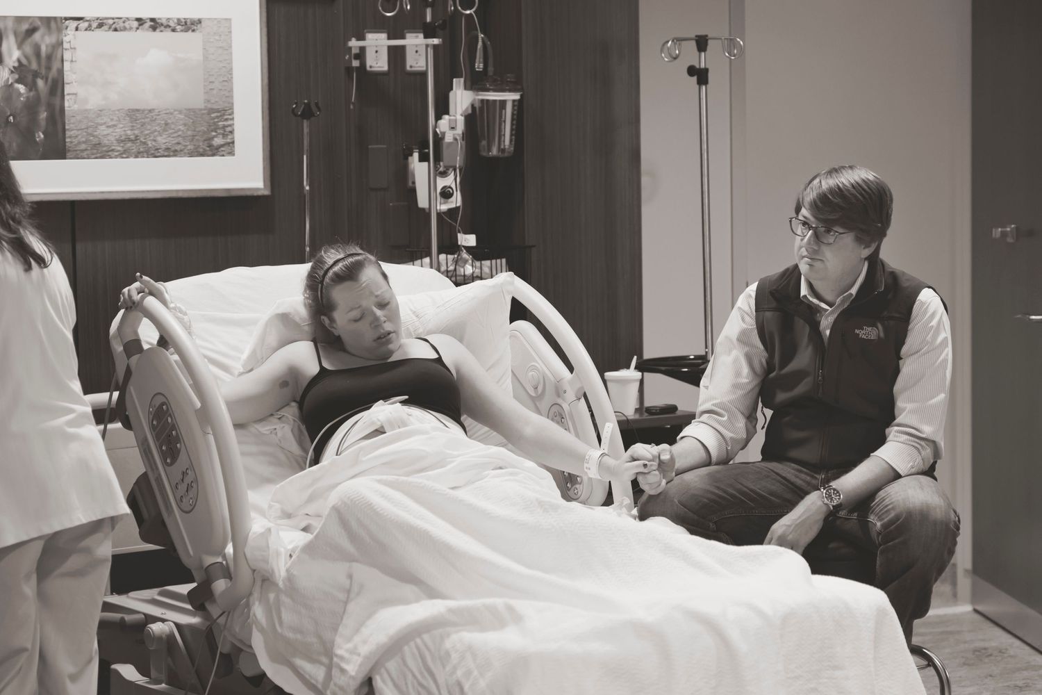 A patient rests in a hospital bed while receiving support during labor and delivery.