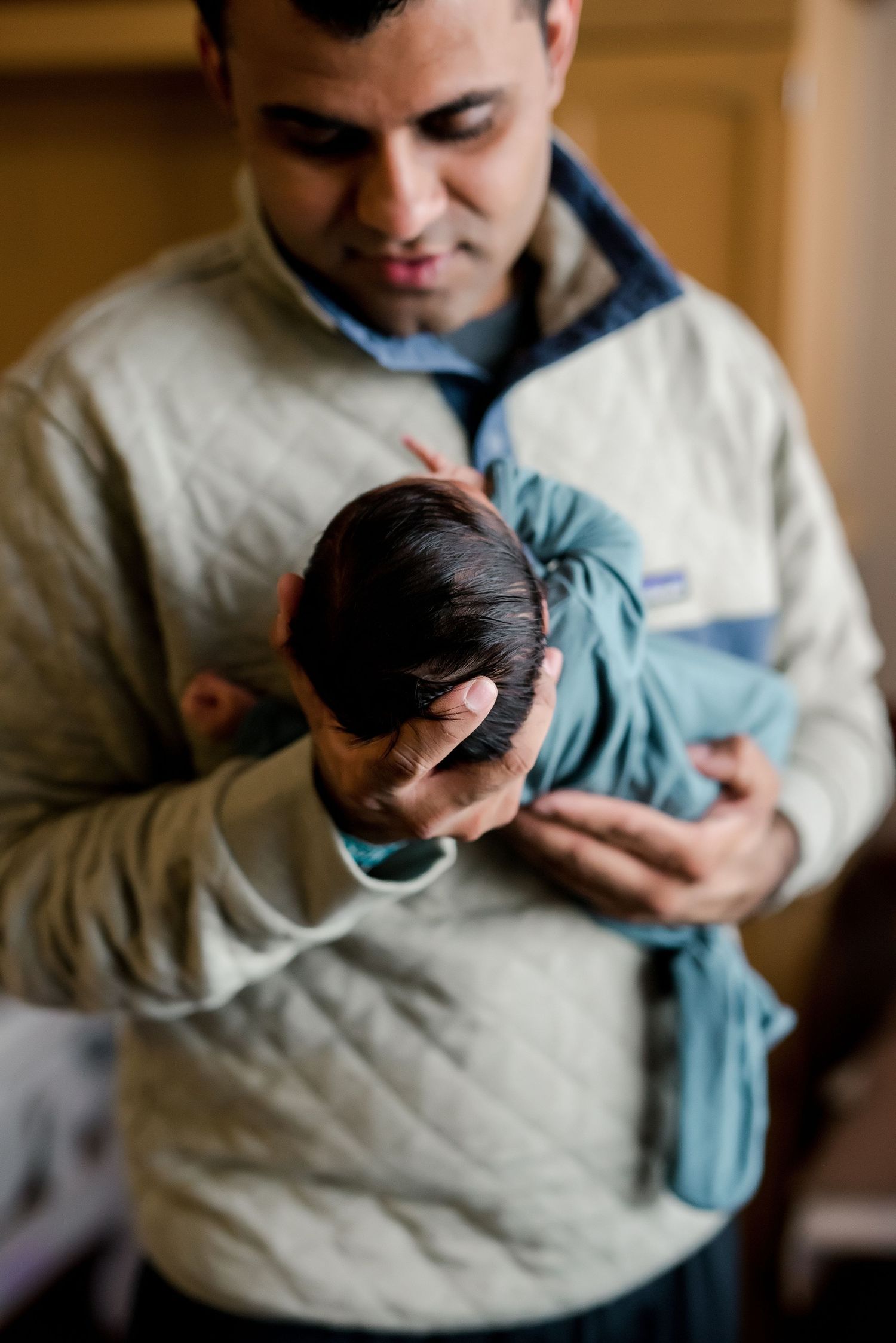 A parent holds and gazes lovingly at their newborn baby wrapped in blue.