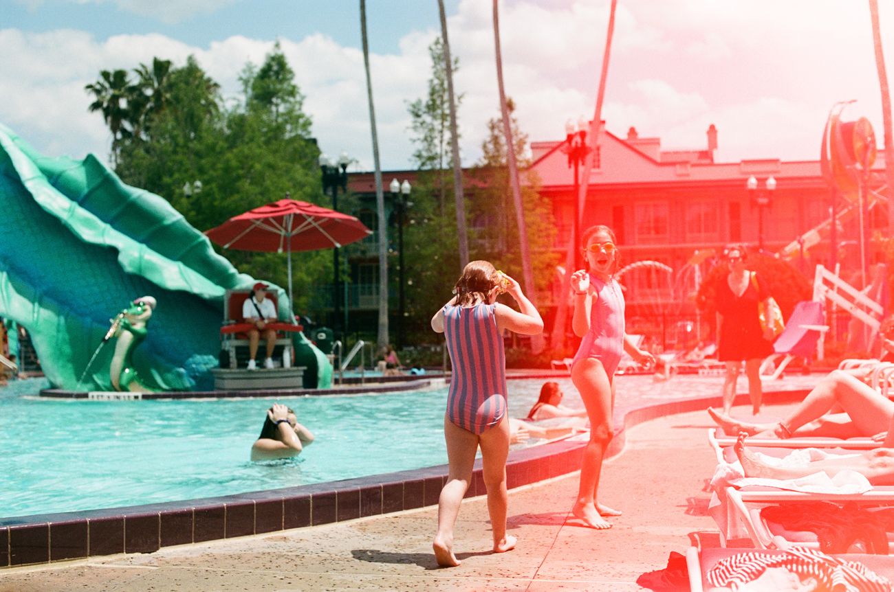 Poolside scene with green alligator sculpture and sun-lit water at Disney resort.