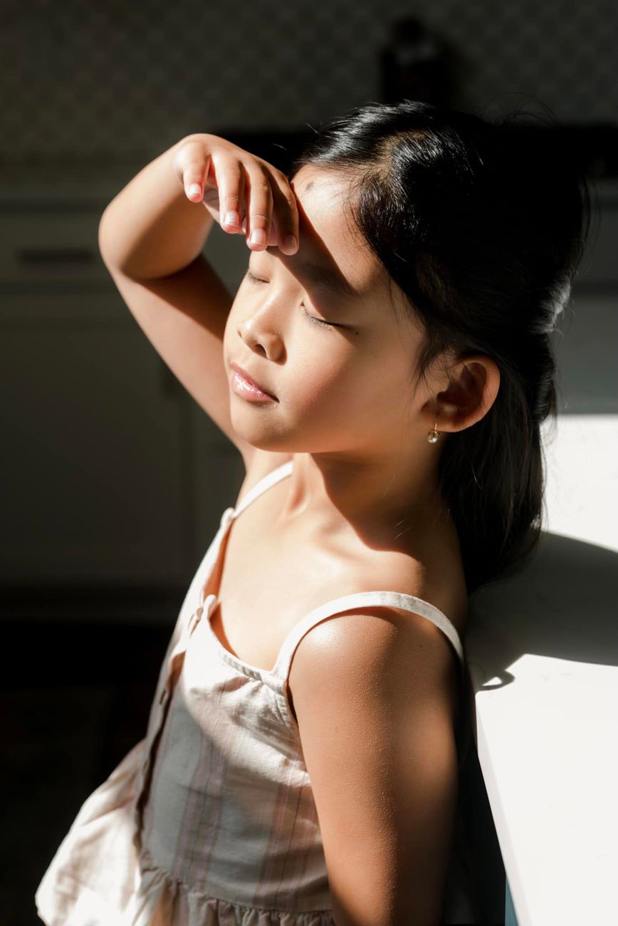 Artistic portrait series showing dramatic shadows and light on figure in white tank top.
