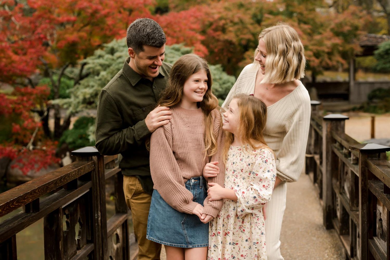 A group enjoying autumn scenery while standing on a wooden bridge surrounded by fall foliage.