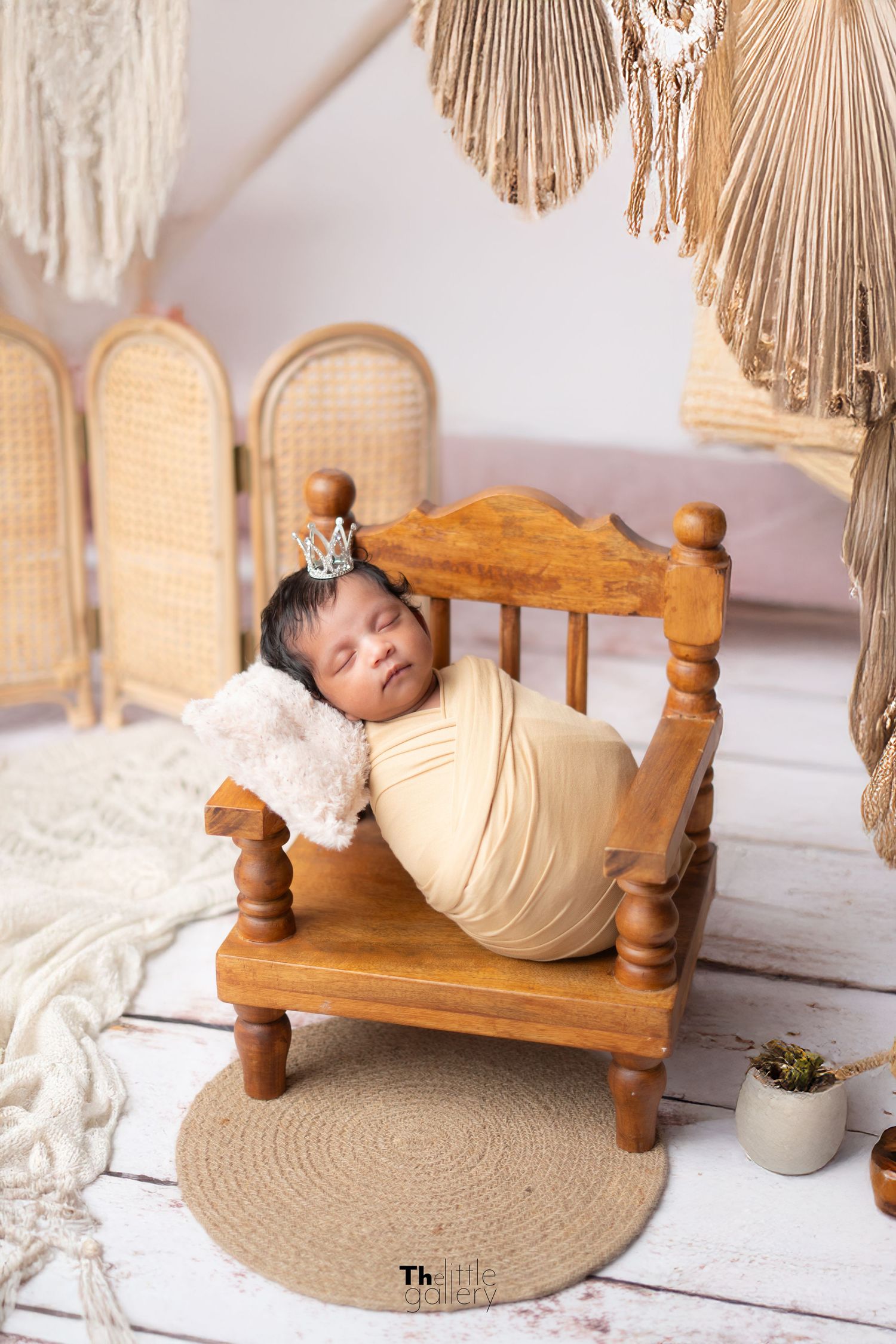 Rustic newborn photography setup with wooden bench and macrame wall hanging.