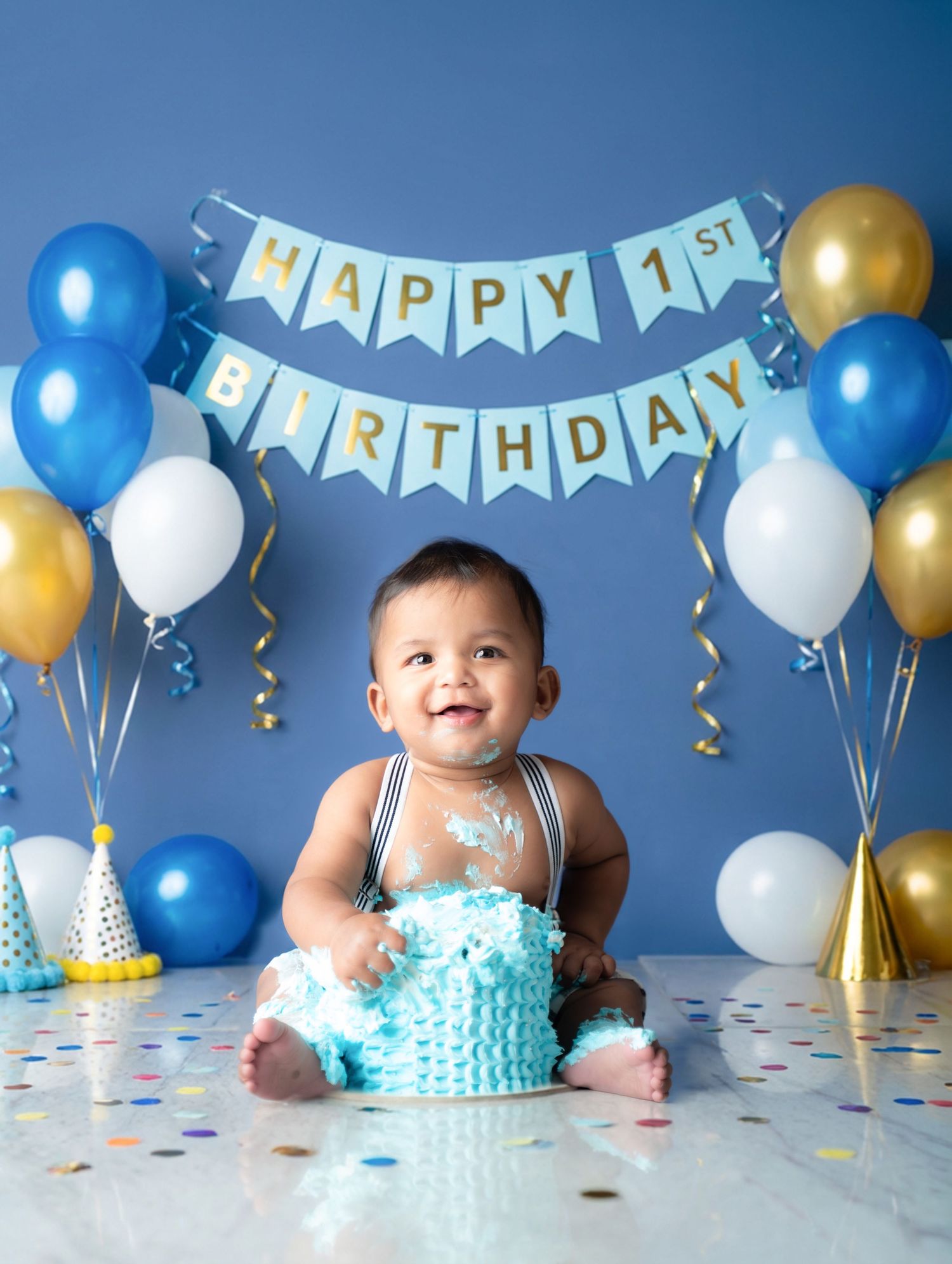 First birthday cake smash photography with blue and gold balloon decorations.