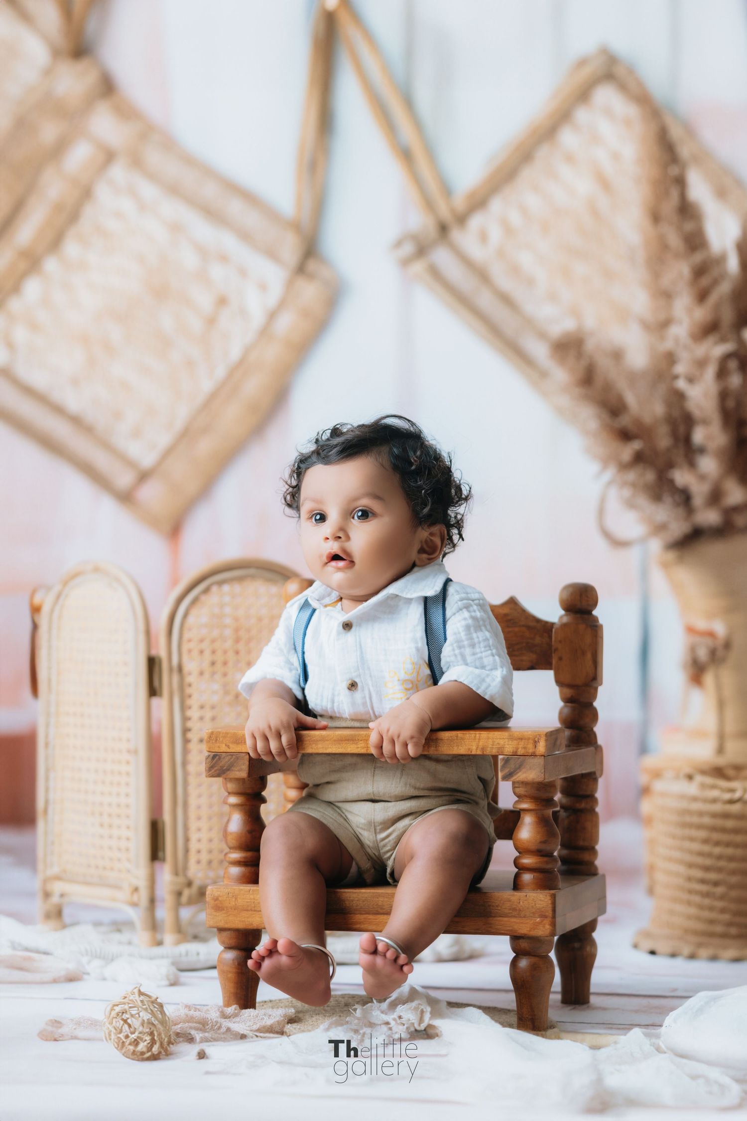 Baby sitting in vintage wooden chair surrounded by wicker and macrame decor.