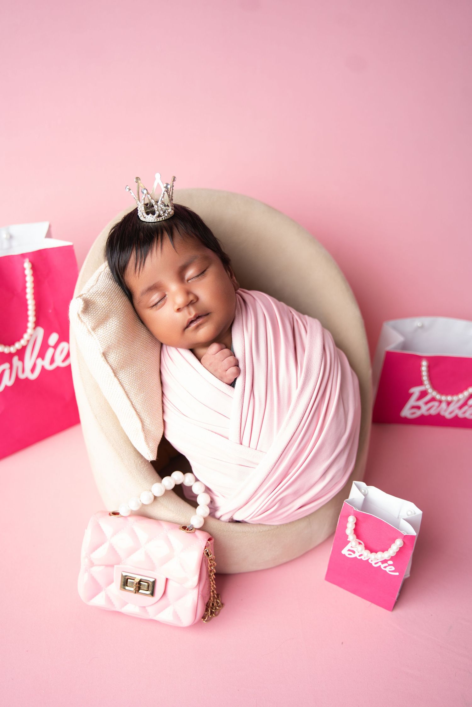 Pink themed newborn photography setup with Barbie shopping bags and soft lighting.