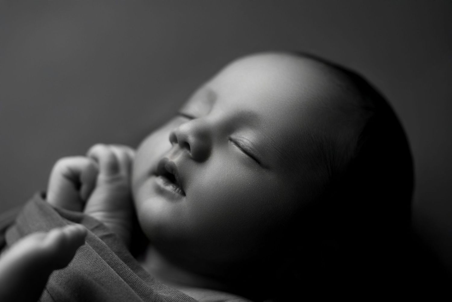 Artistic black and white portrait of sleeping infant with gentle shadows.