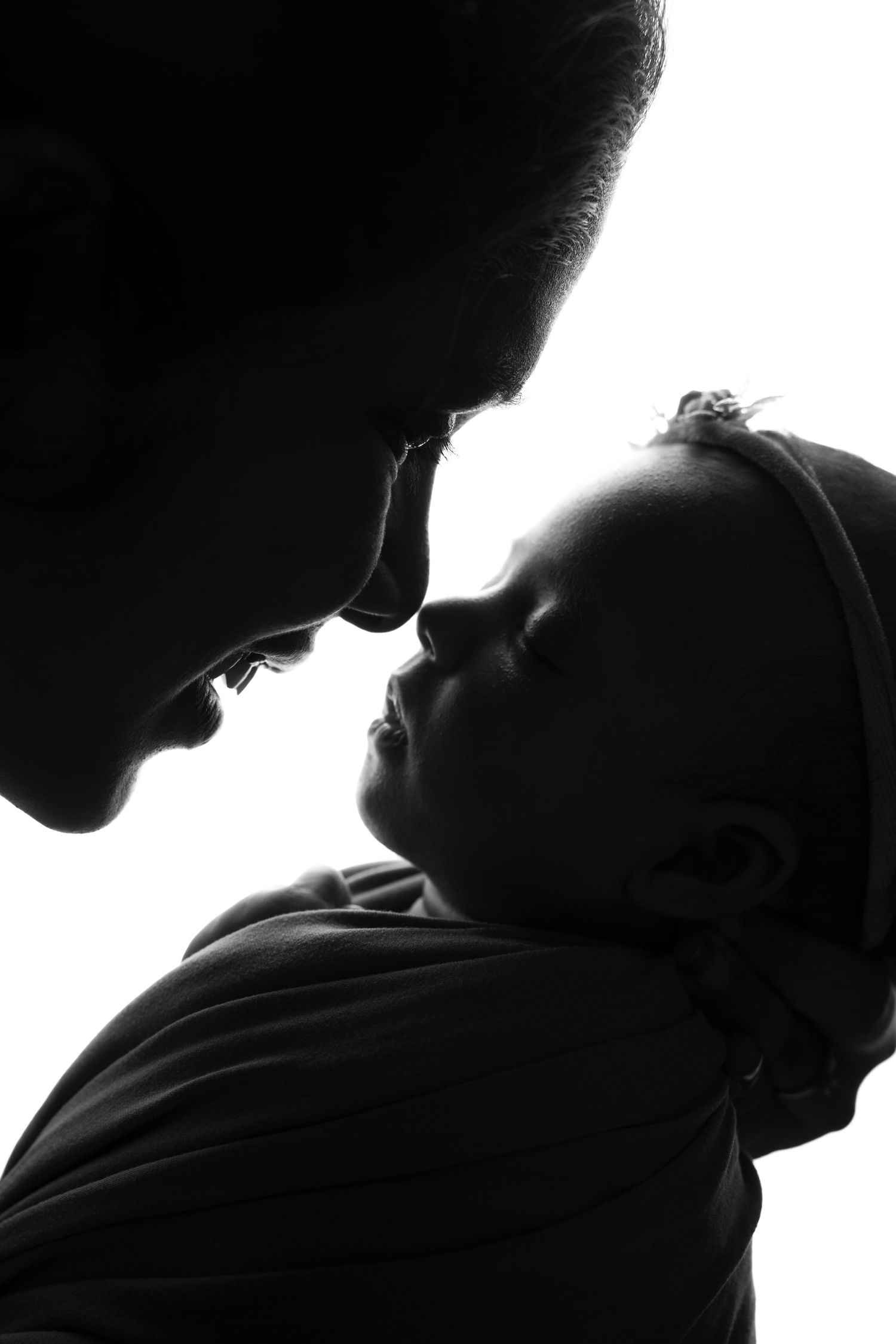 Intimate black and white silhouette of parent and baby in tender moment.