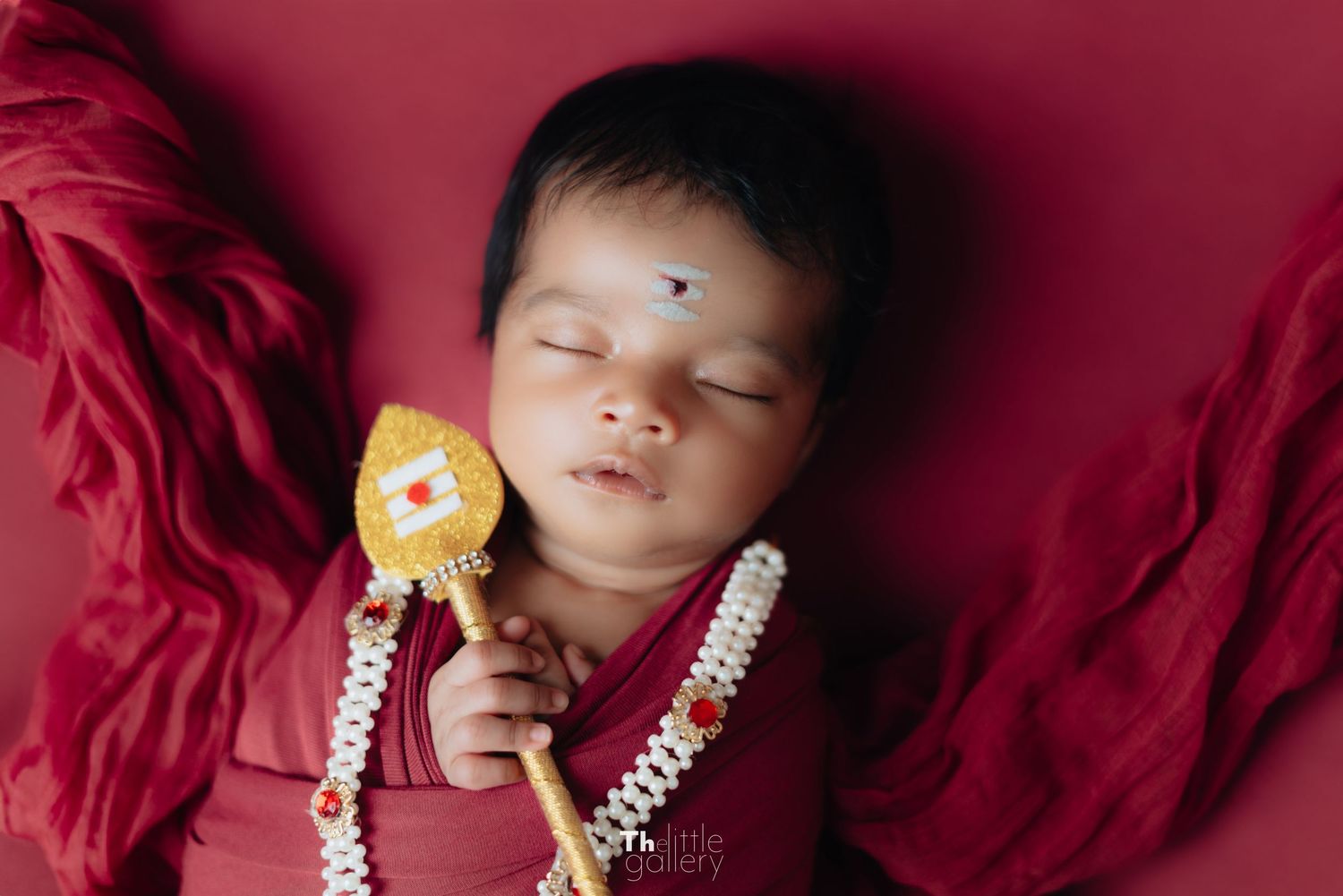 Deep red themed newborn photography with elegant jewelry accents.