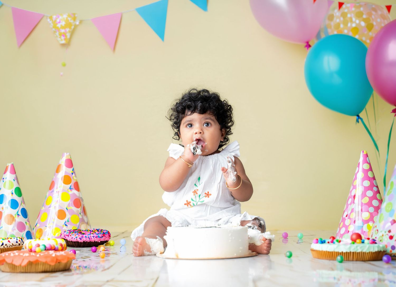 Colorful birthday party setup with pink and blue balloons and festive party hats.
