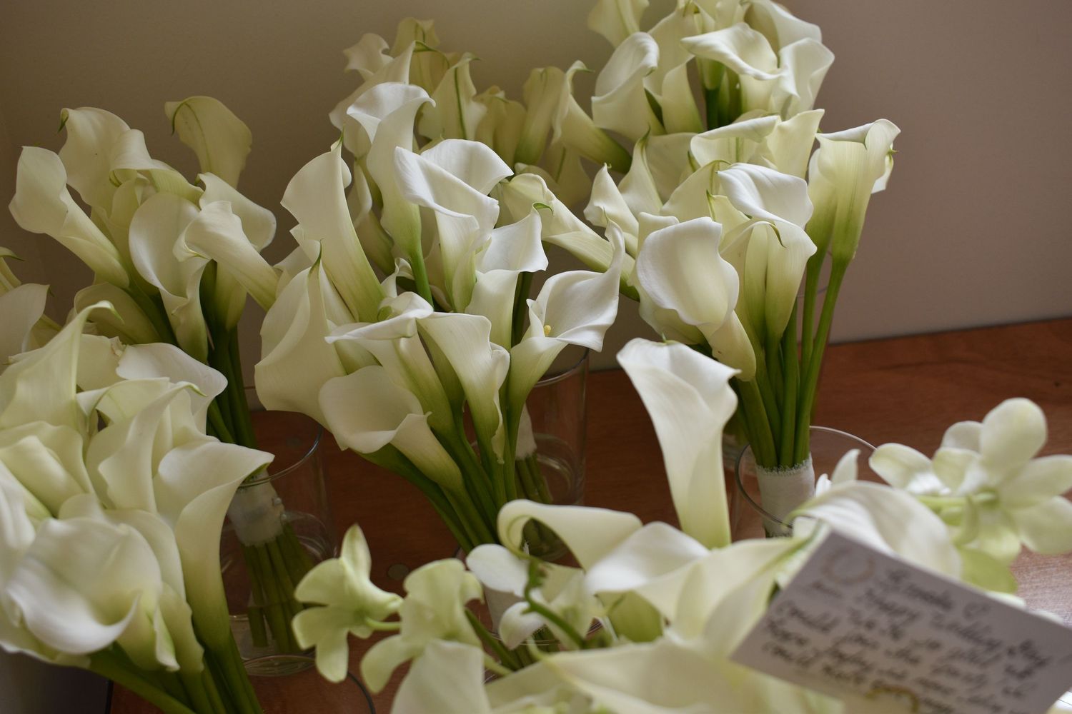 Multiple bouquets of white calla lilies arranged on a table, perfect for a wedding or special occasion.