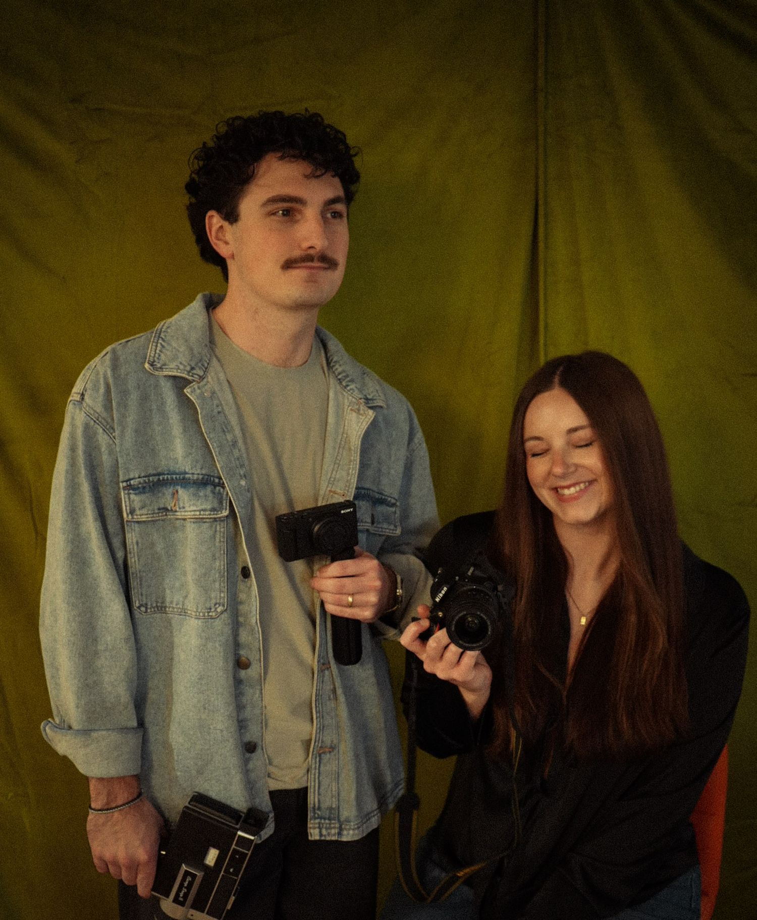 A couple shares playful moments with a vintage camera in a series of candid shots against a dark backdrop.