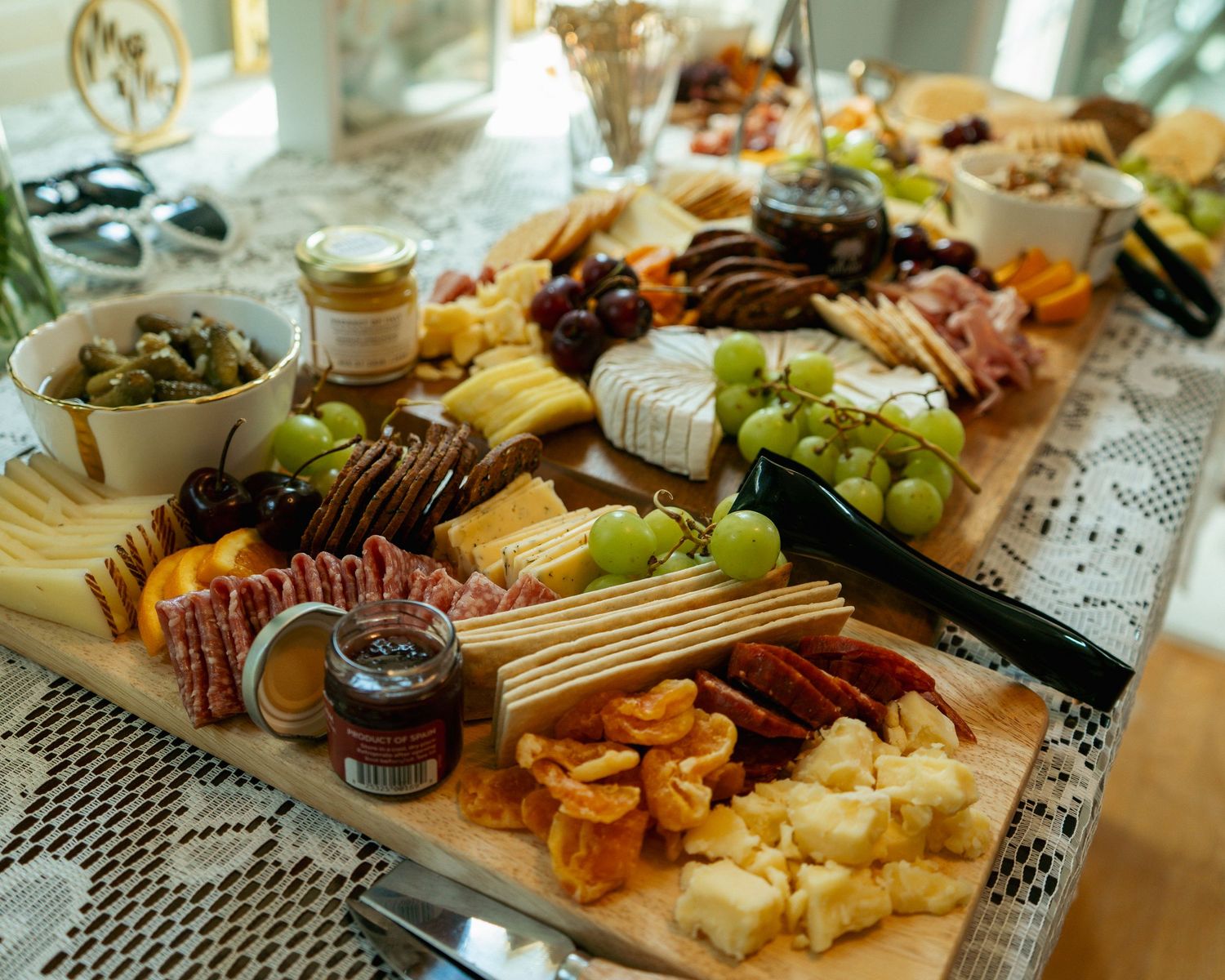 Elegant charcuterie board with assorted cheeses, cured meats, grapes, crackers, and condiments on a wooden platter.