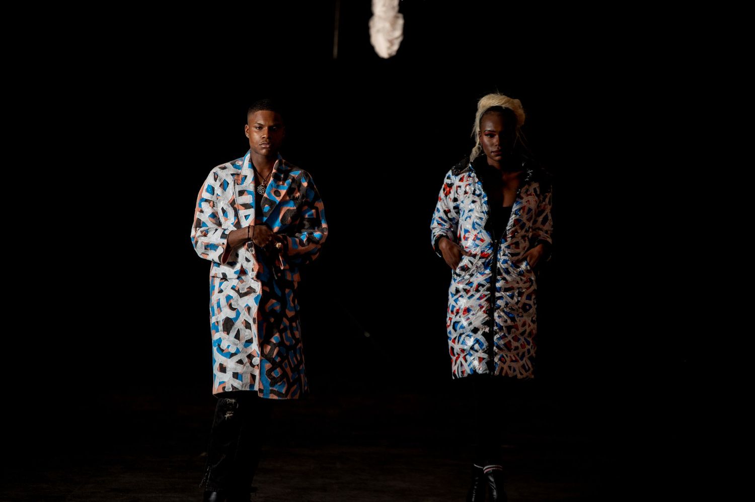 Two models stand in matching colorful printed robes against dark background.