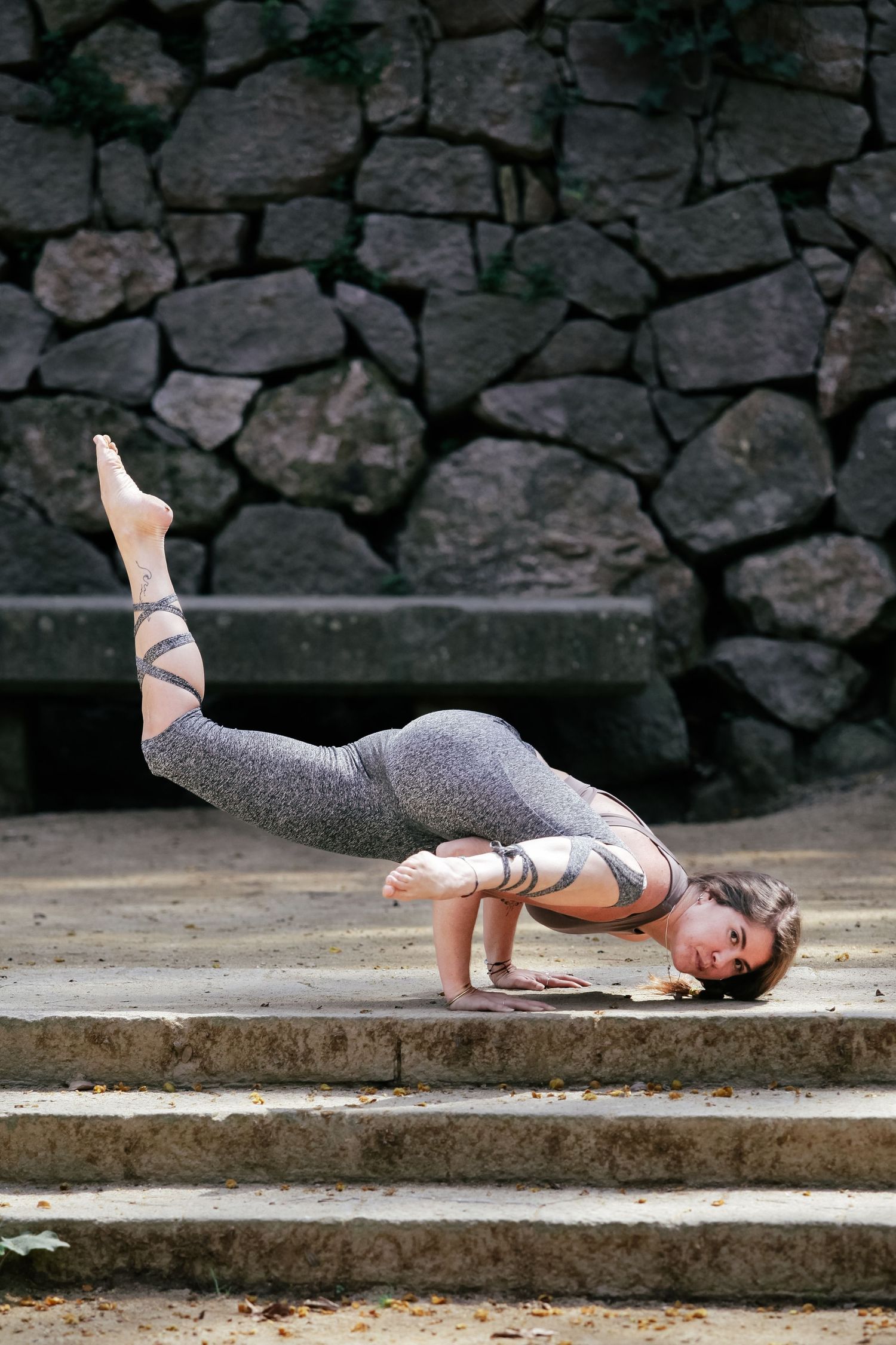 Dancer stretching gracefully on stone steps in athletic wear.