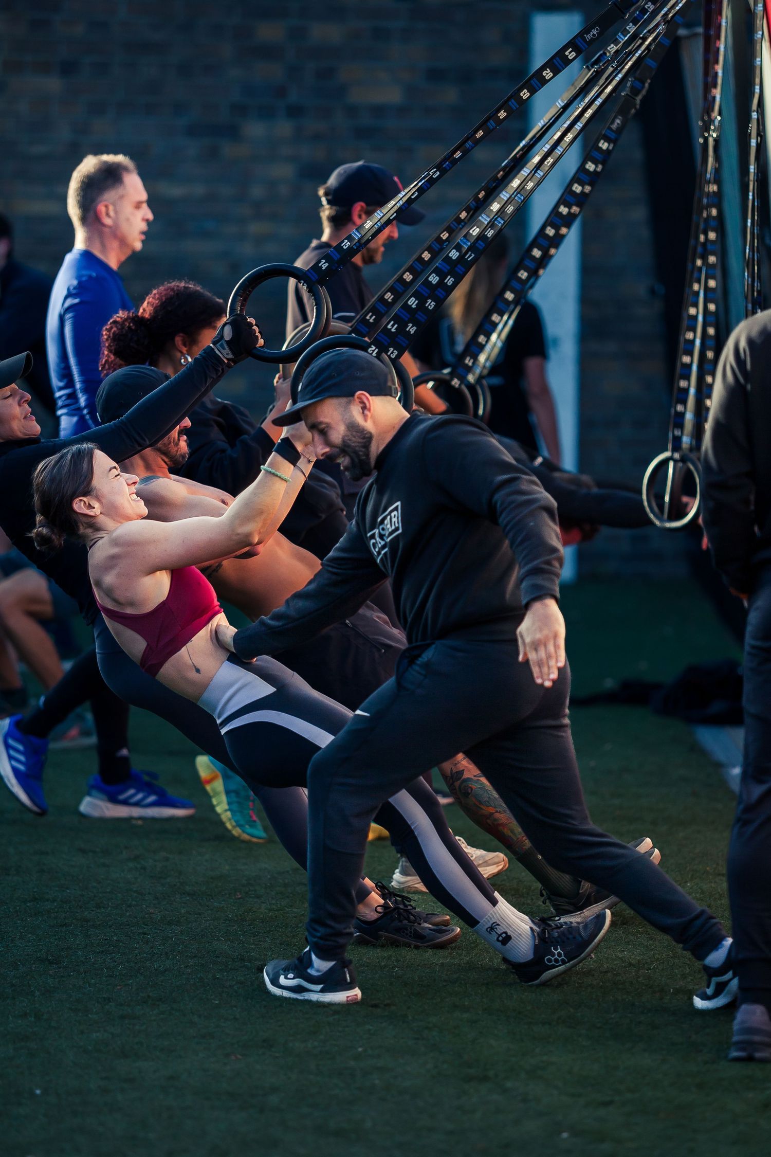 Group fitness class using suspension training straps outdoors.