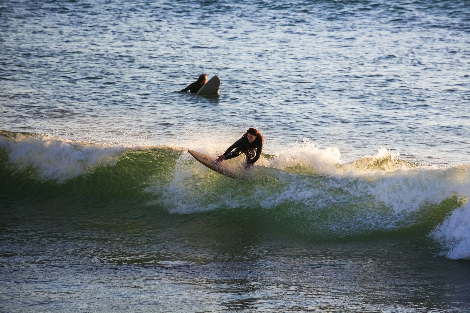 Silhouette of surfer riding ocean wave at sunset.