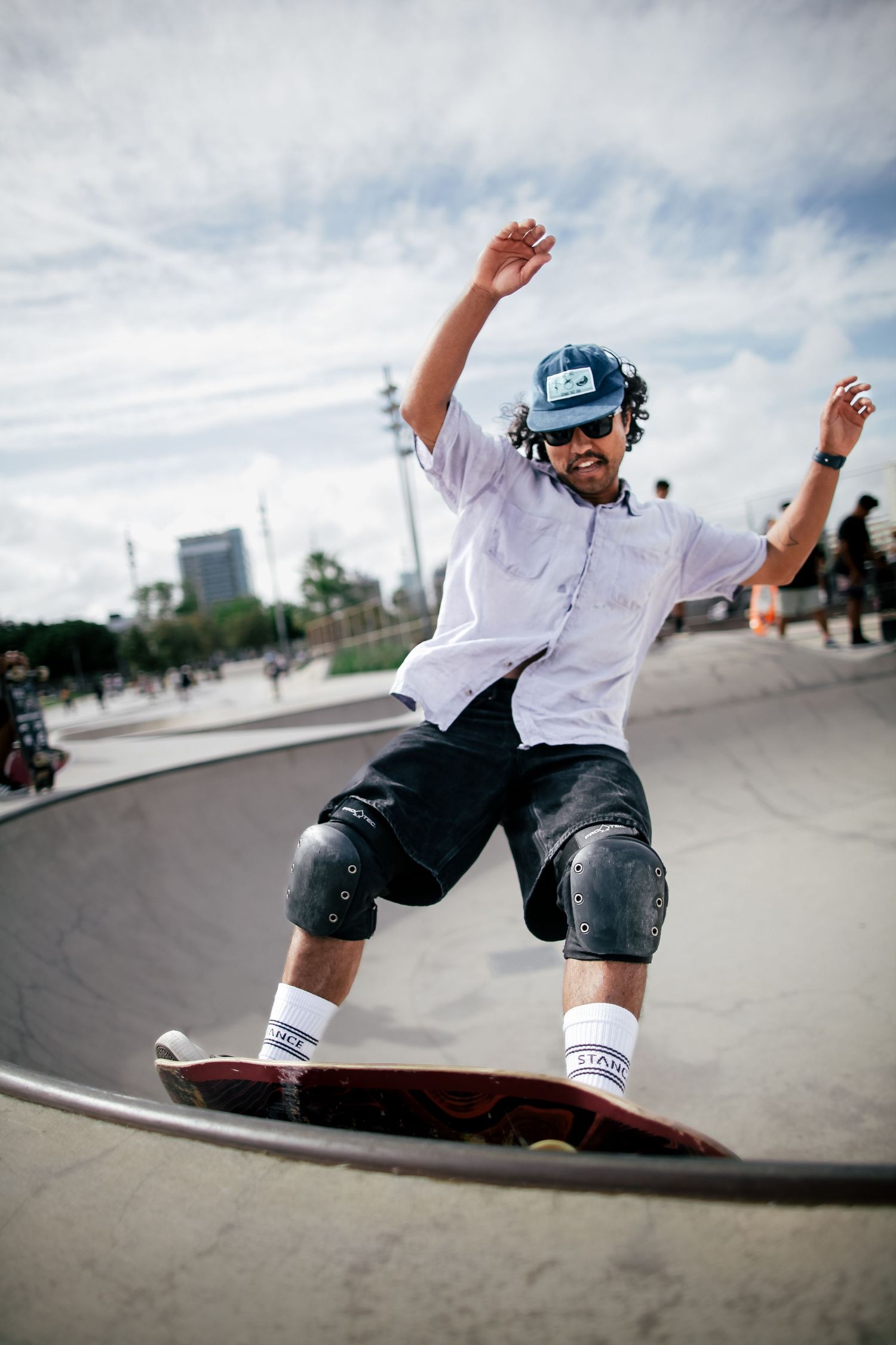 Skateboarder in casual wear performing tricks at an outdoor skate park.
