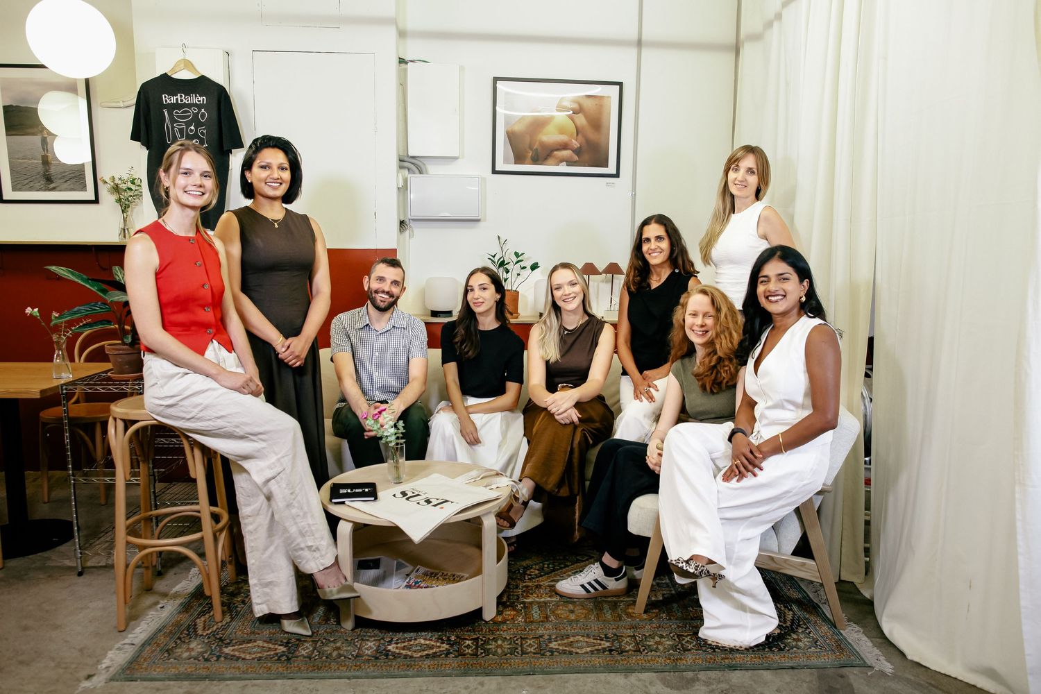 Group of people seated in white room for casual gathering or meeting.