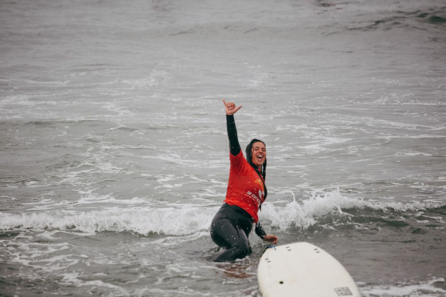 People swimming and playing in ocean waves on a cloudy day.
