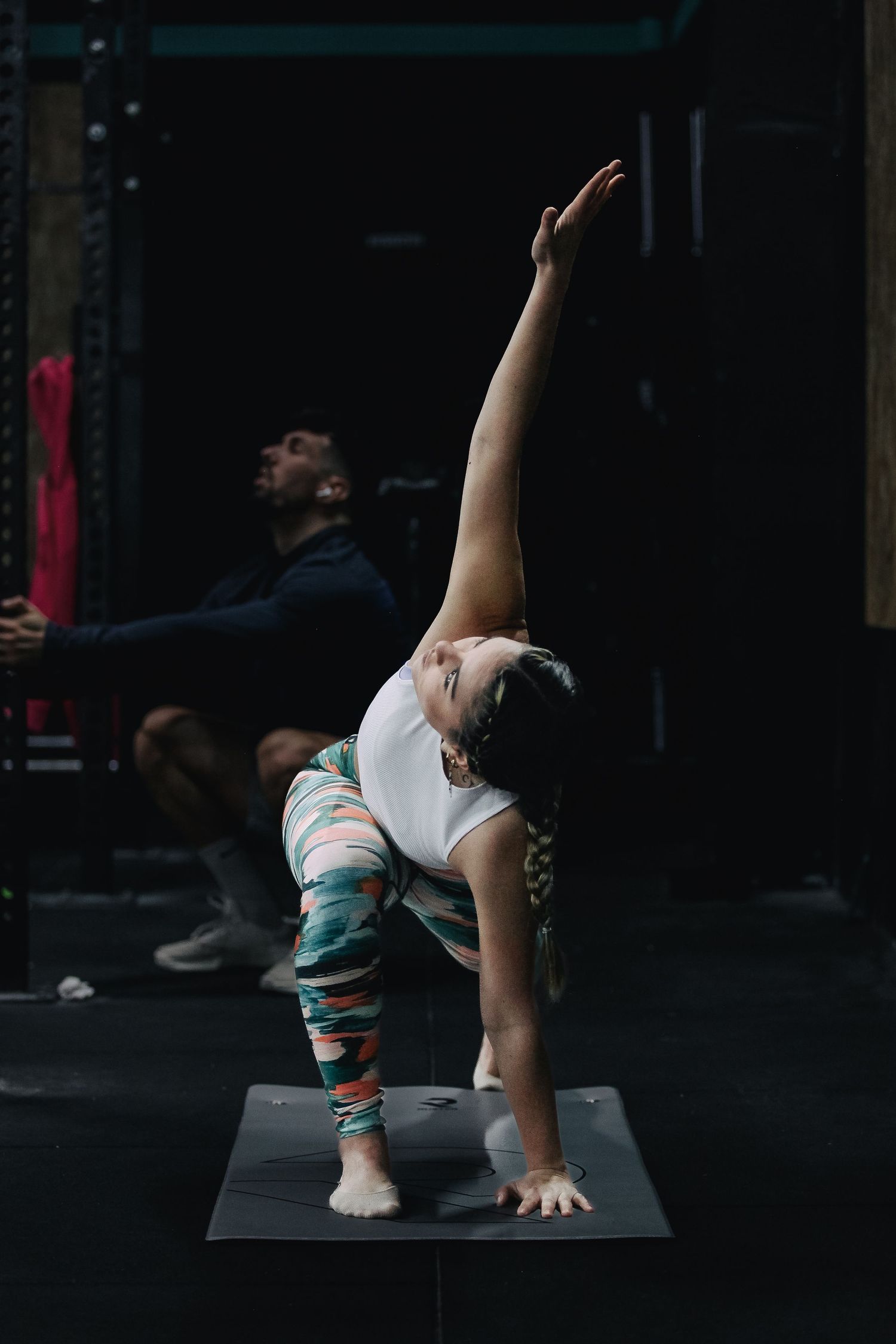 Person performing a yoga pose on a dark mat demonstrating flexibility and balance.
