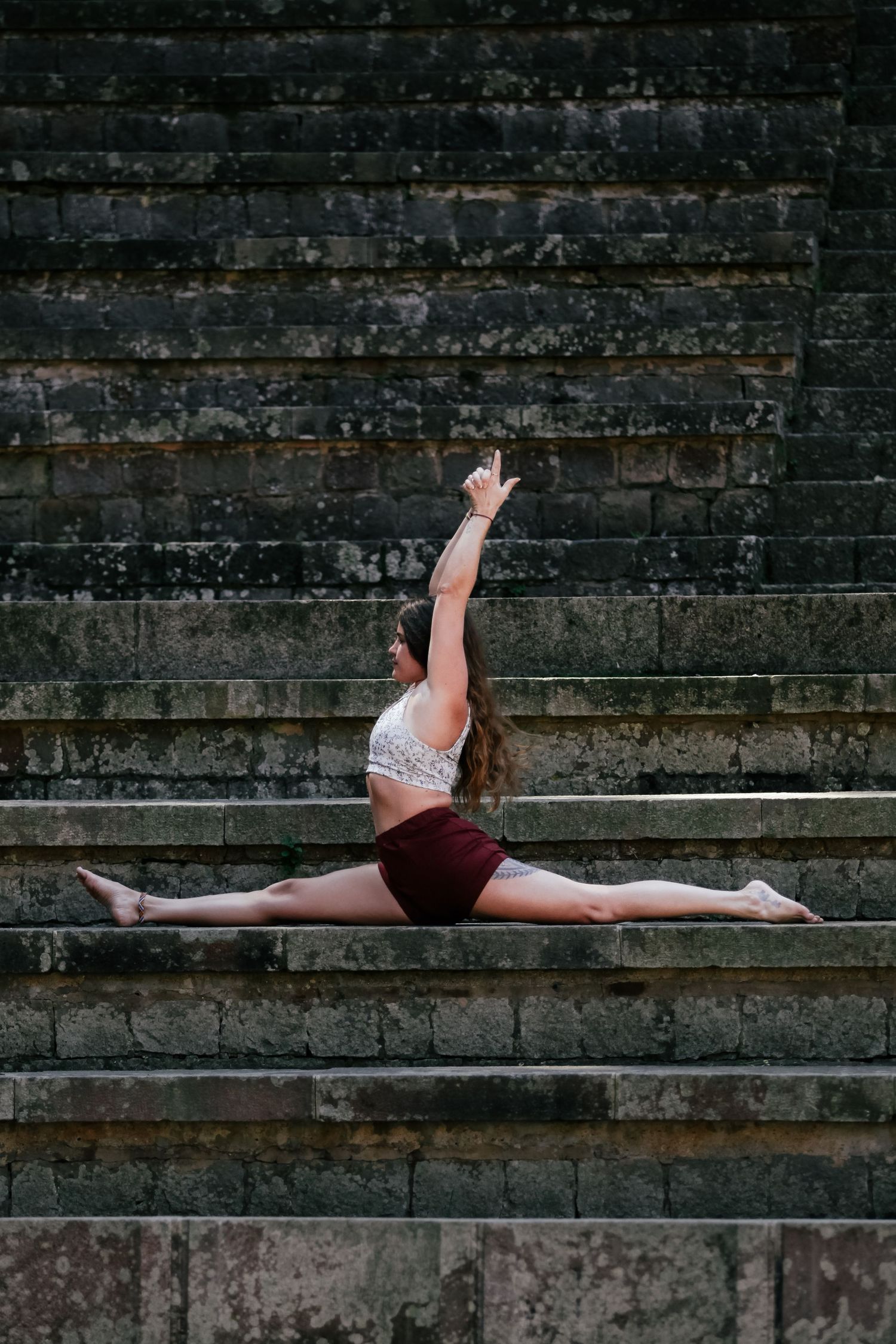 Gymnast performing a split pose on concrete steps showing flexibility and strength.