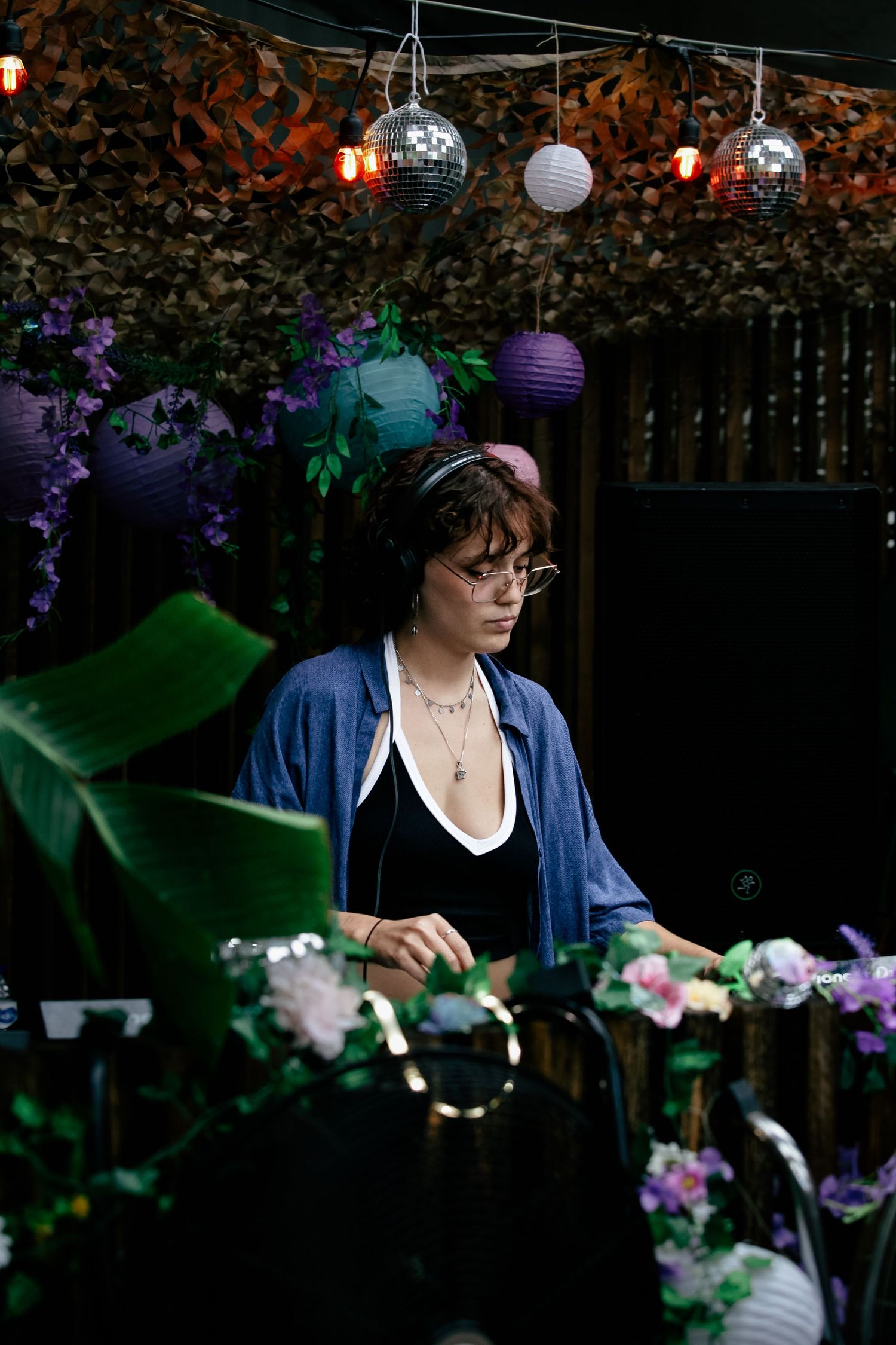 Decorative purple lanterns and floral arrangements adorn an outdoor evening party setting.