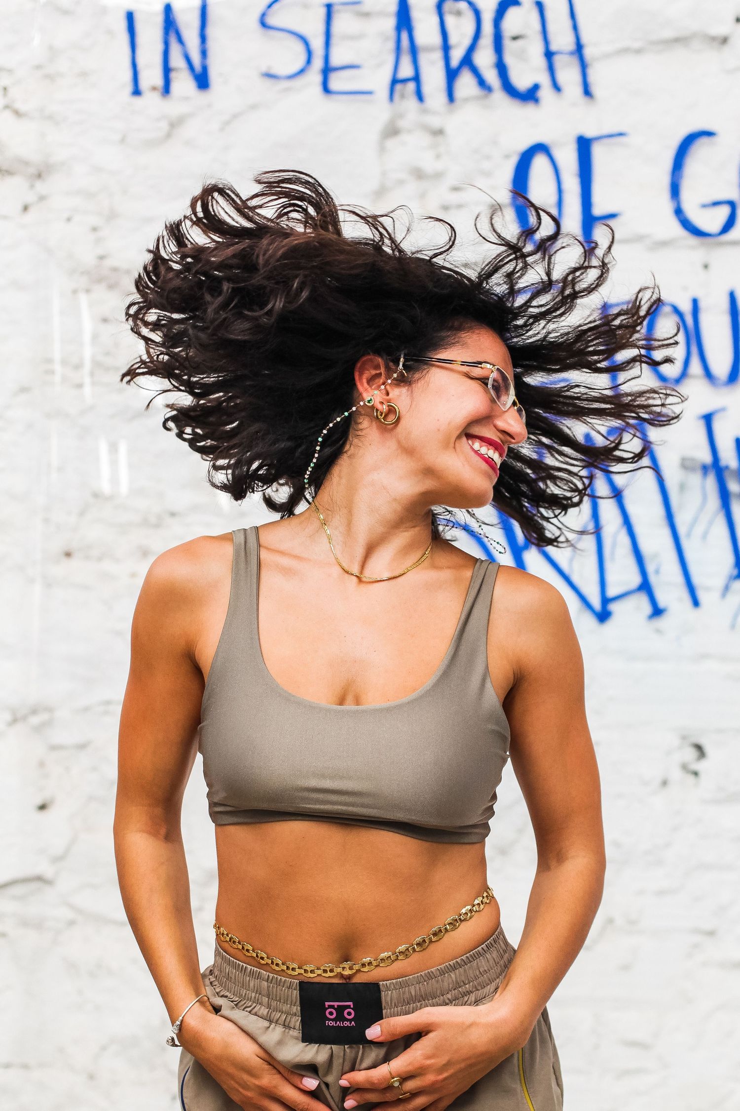 Energetic dance movement sequence against white wall with blue graffiti text.
