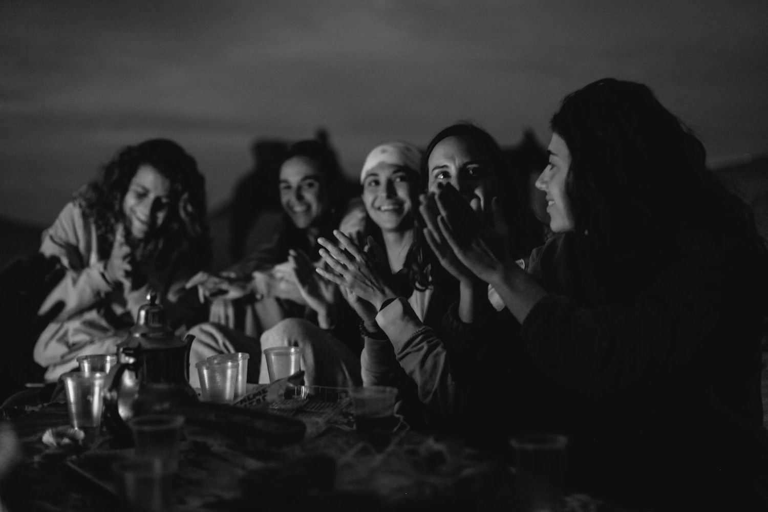 Friends enjoying drinks and conversation around a table at night.