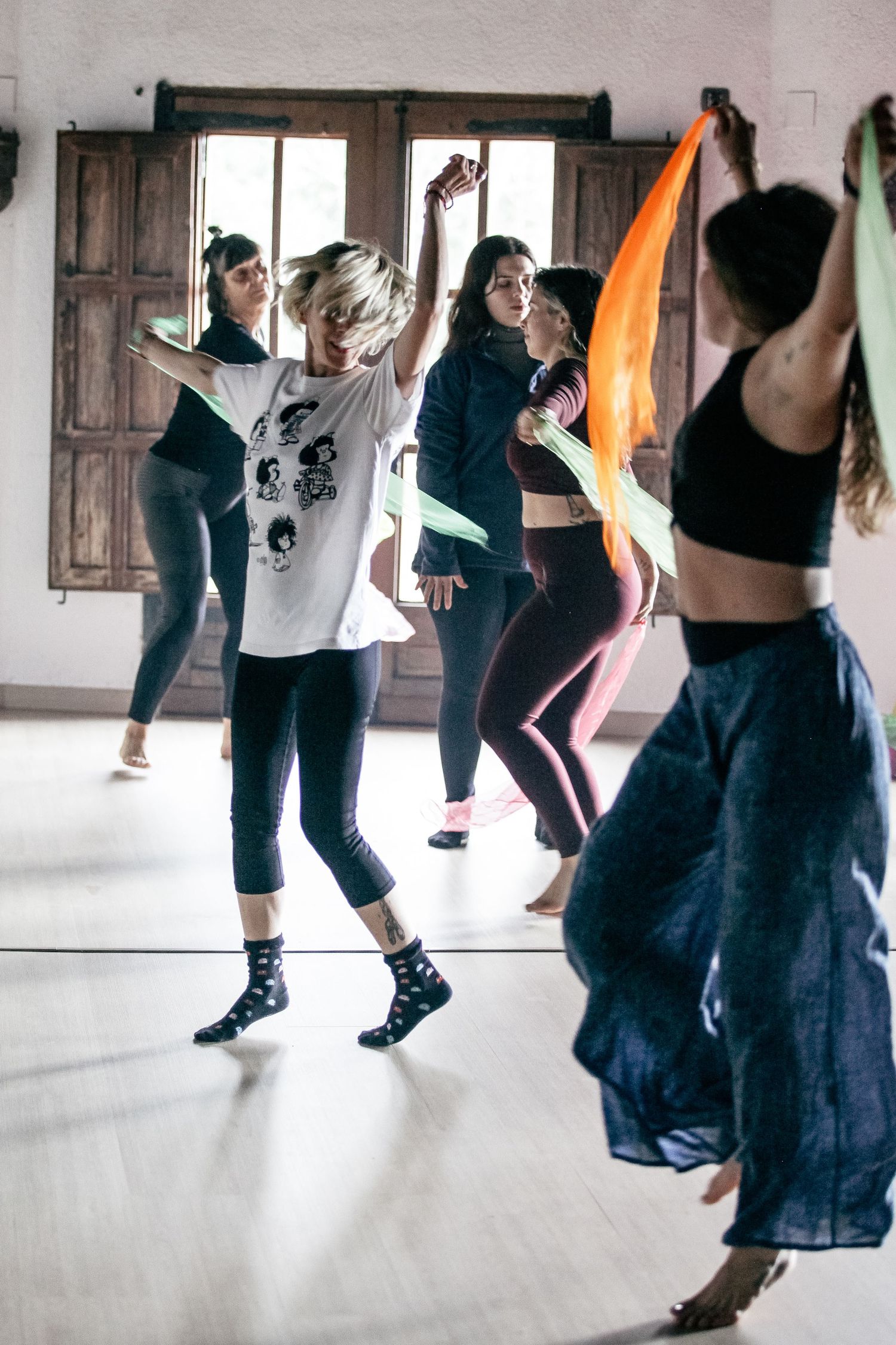 Dance class participants practicing movements in a bright studio space.
