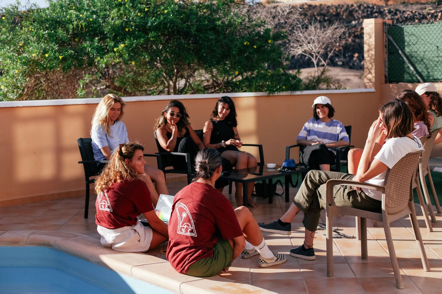 Group gathered outdoors enjoying conversation and refreshments on a sunny patio.