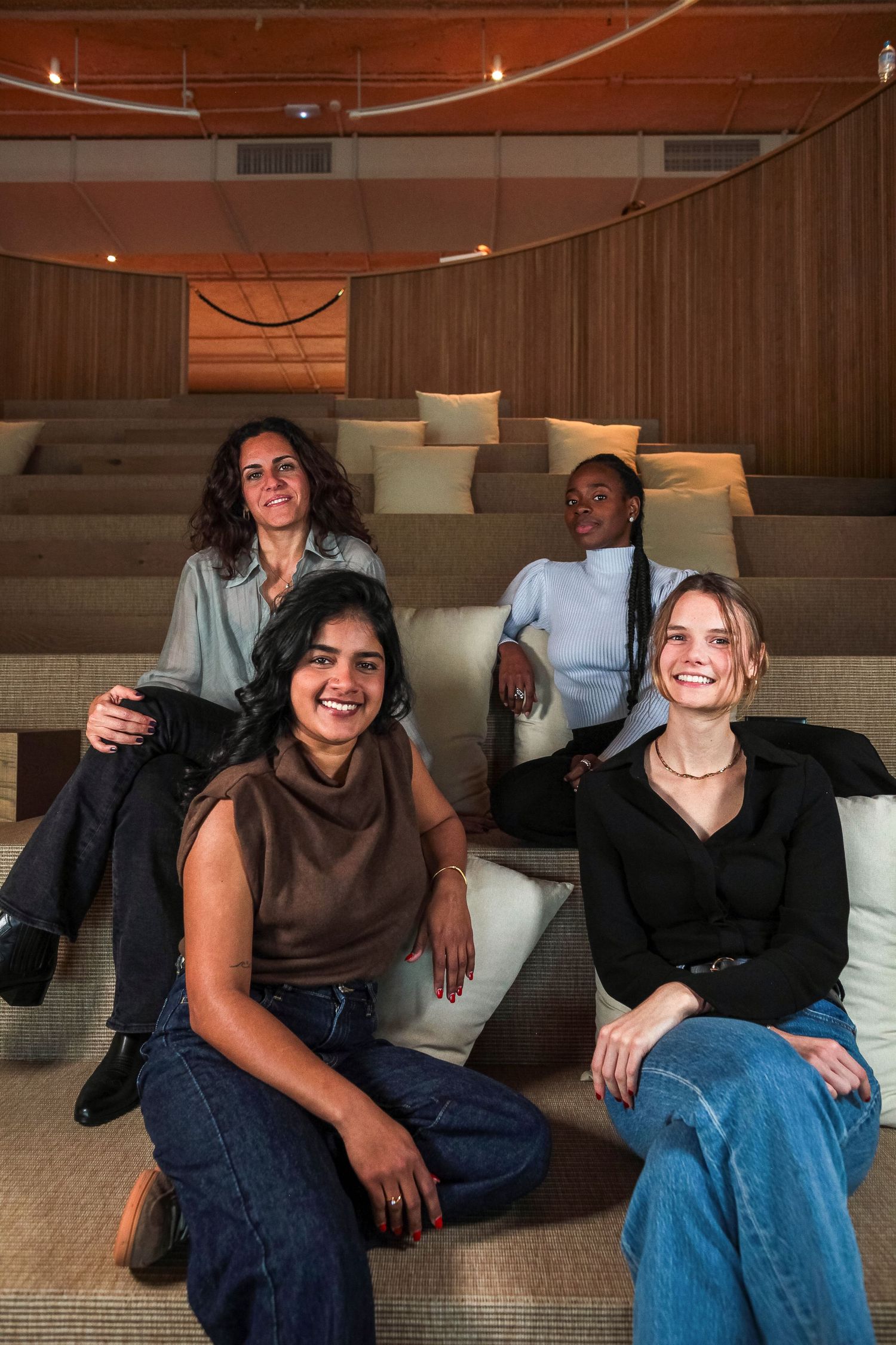 Friends relaxing together on comfortable lounge seating in a wood-paneled room.