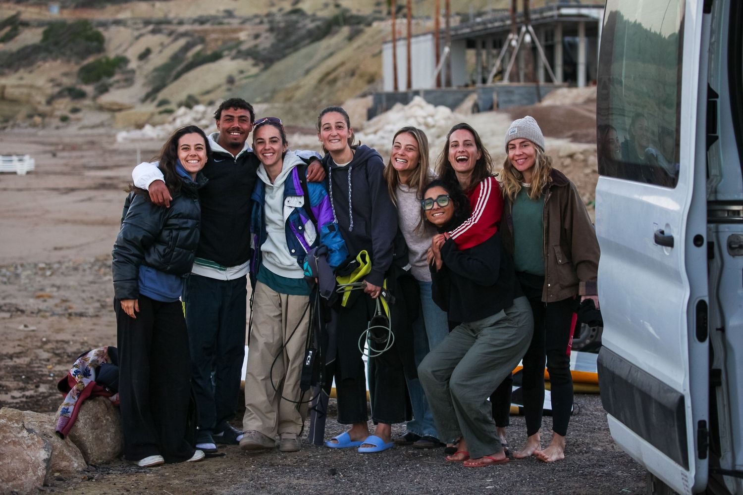 A group of friends posing together next to a van during an outdoor adventure.