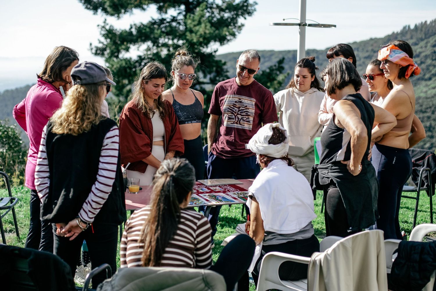 Group of people gathered outdoors near a cross on a hillside.