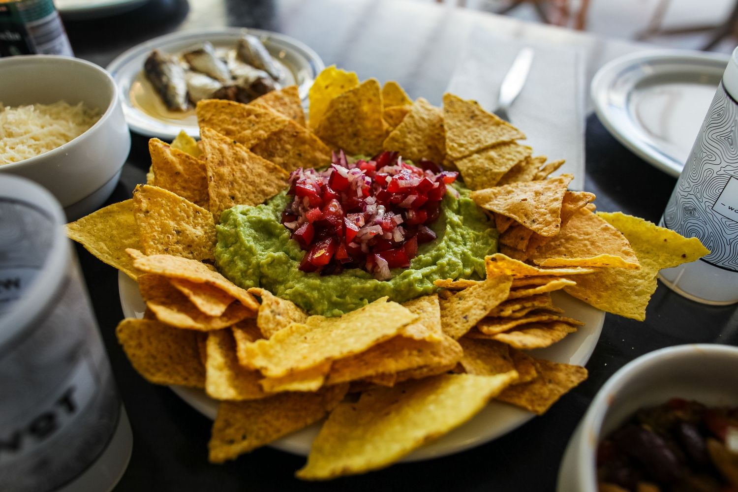 A plate of tortilla chips topped with fresh guacamole and pomegranate seeds.