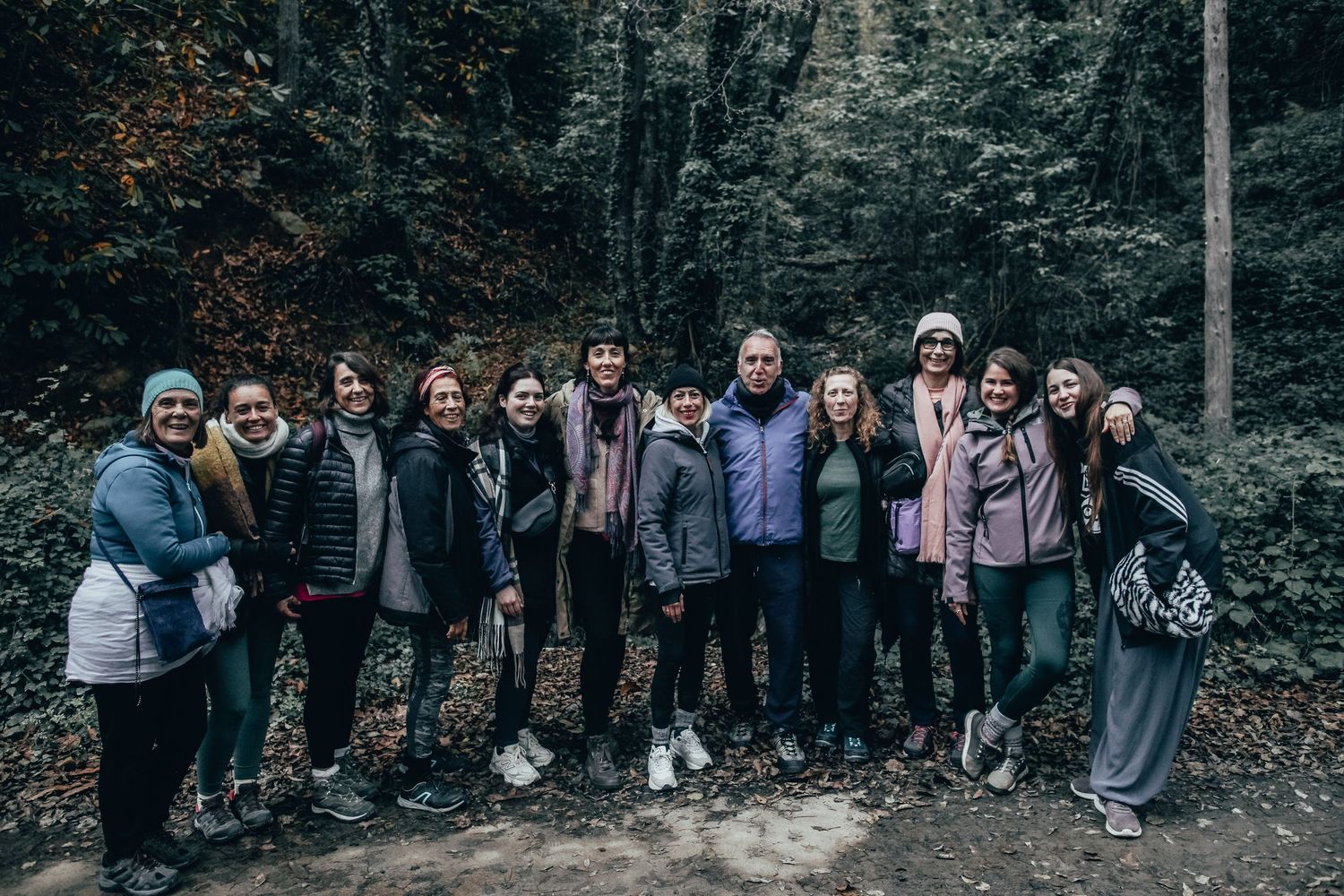 Large group photo of people standing together against a wooded background.