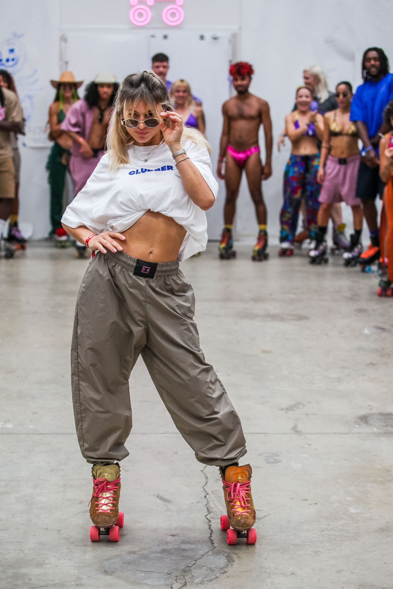 Person wearing baggy cargo pants and roller skates performing dance moves at an indoor event.