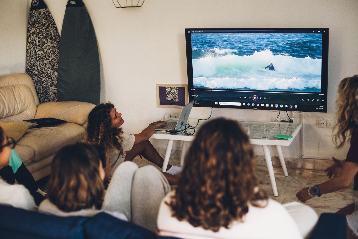 People watching a movie or presentation on a large TV screen in a living room setting.
