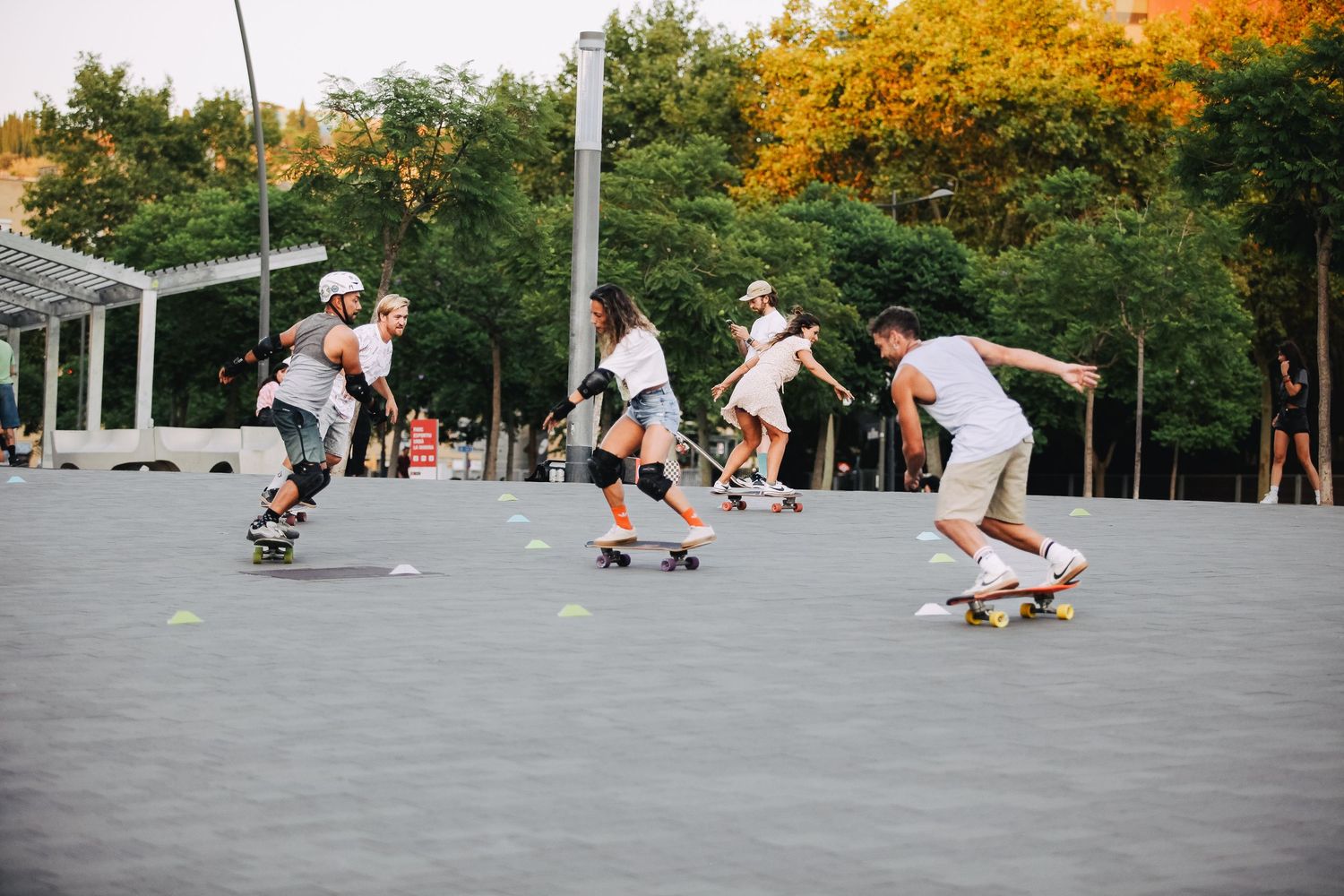 Skateboarders practicing tricks and riding on an outdoor path during autumn.